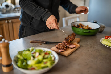 Man preparing healthy dinner with sliced steak and salad