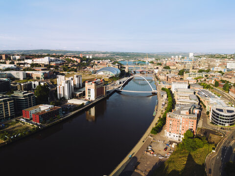 Newcastle upon Tyne: 9th August 2025: Buildings line the Newcastle Quayside at dawn. Bridges stands over the river, reflecting in the water below. Drone view