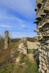 Fototapeta premium Ancient stone ruins on a hill under a bright blue sky with wispy clouds