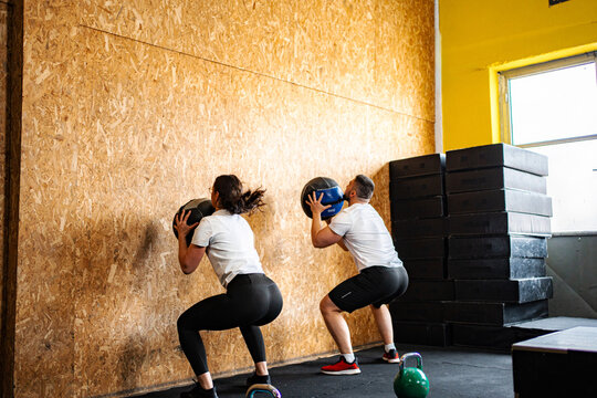Two people doing wall ball squats during fitness workout