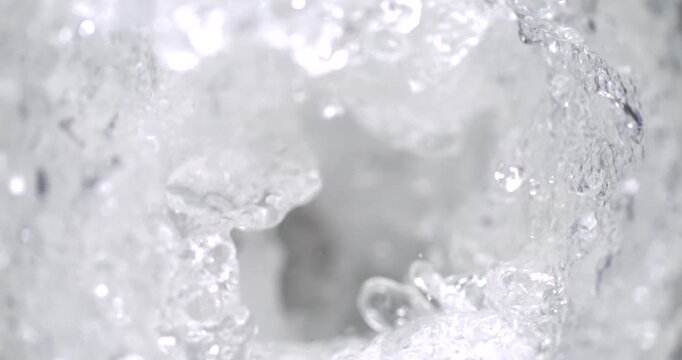 Water splashes in a clear container during a morning activity in a sunny kitchen