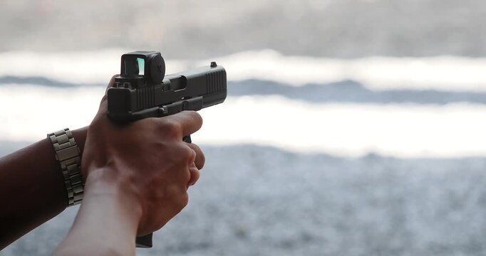 Man practices shooting with a handgun at a shooting range.
