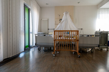 Modern hospital family room with newborn baby in crib, clean healthcare interior, maternity ward, calm recovery environment with natural light and medical equipment