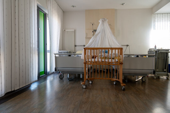 Modern hospital family room with newborn baby in crib, clean healthcare interior, maternity ward, calm recovery environment with natural light and medical equipment