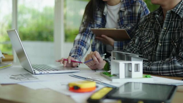 Architect and engineer working brainstorming and measuring for cost estimating on paperworks and floor plan drawings about design architectural and engineering for houses and buildings.