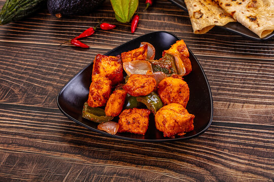 Indian Paneer Tikka Masala inl with Roti bread on a dark wooden table