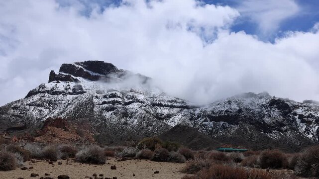 Snow covered Teide volcano landscape after storm Therese in Tenerife Canary Islands, dramatic clouds, volcanic terrain and winter conditions in subtropical island