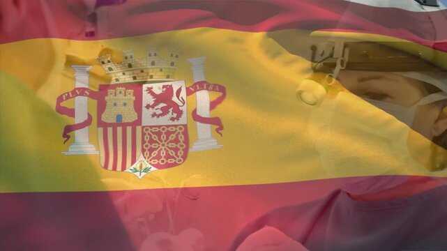 Animation of flag of spain over caucasian surgeons with face masks during surgery