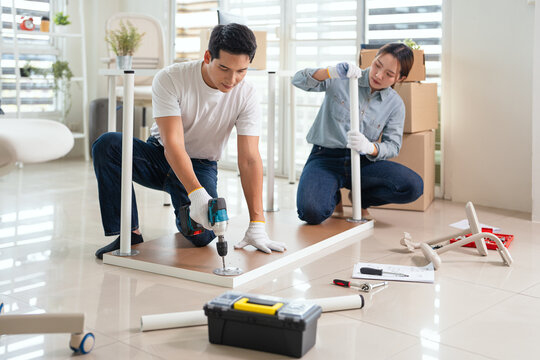 Couple assembly furniture in new house apartment. Relocation lifestyle