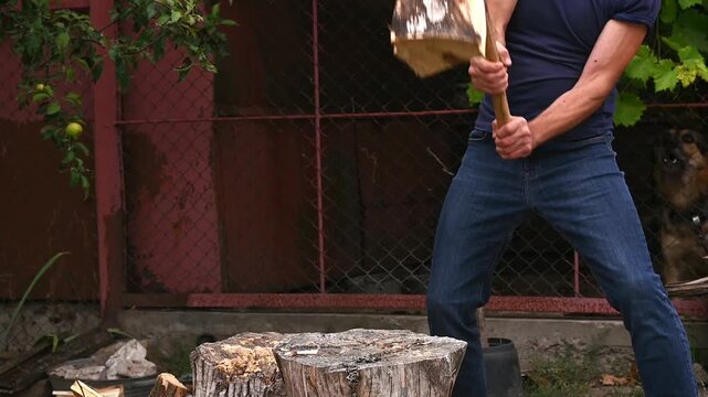 man chopping wood with axe, but log remains unbroken after strike. close-up of action with muscle tension and effort in male posture. log does not split on first strike. chop firewood outdoors.