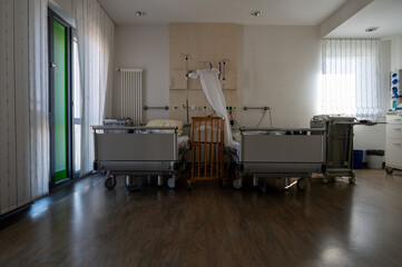 Modern hospital family room with newborn baby in crib, clean healthcare interior, maternity ward, calm recovery environment with natural light and medical equipment