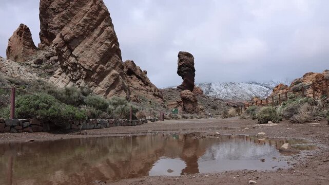 Roques de Garcia rock formations in Teide National Park Tenerife with rare puddle from melted snow, dramatic volcanic landscape and cloudy sky after storm