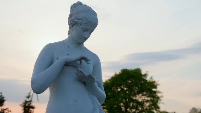 Serene Marble Figure Scene. Peaceful Park Setting Featuring Female Marble Sculpture At Sunset. Creative