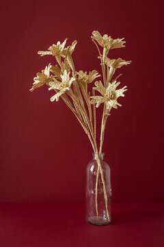 A glass vase with a bouquet of flowers made from straw on the red background. Straw weaving