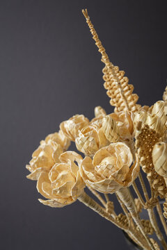 The bouquet flowers is made of straw on a gray background. Straw weaving. Small depth of field.