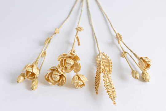 Three flowers are made of straw on a white background