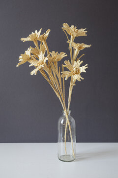 A glass vase with a bouquet of flowers made from straw on a gray background. Straw weaving