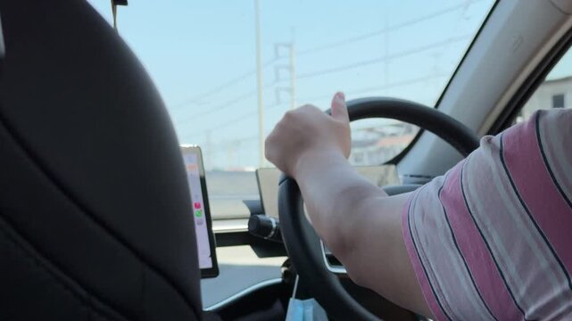 East Asian man driving and checking GPS map during the day.