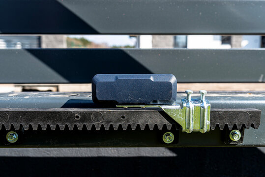 Sliding gate installation with safety sensor and gear rack