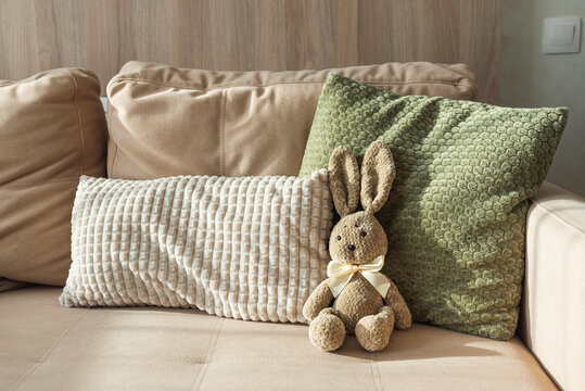 Plush Bunny sitting on sofa. Cozy Easter Decoration