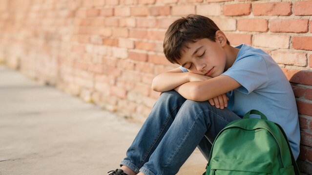 Young boy resting against brick wall