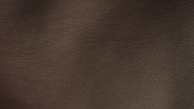 A close-up of the brown faux leather texture. The detailed surface of the faux leather features a natural grain pattern. High quality 4k footage
