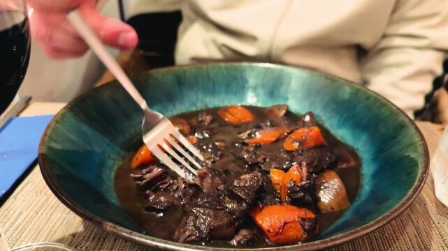 Beef bourguignon, traditional French stew with tender beef slow cooked in red wine with mushrooms, onions, and vegetables. Rich sauce and classic rustic cuisine. High quality 4k footage