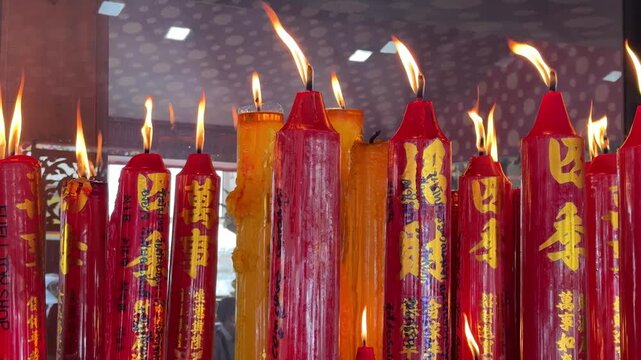Large red and yellow candles in a Buddhist temple compound.