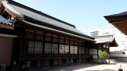 Naklejka premium Traditional Japanese Wooden Architecture with Curved Roof in Urban Setting, Kyushu Japan