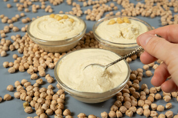 Fototapeta premium Traditional hummus in a spoon among scattered raw chickpeas.