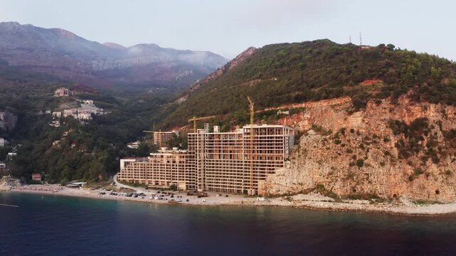 Flying drone 4K footage around abandoned Perazica Do beach gigantic AS hotel during sunset light hours. Gost of Yugoslavia from 1973. Petrovac, Adriatic seacoast, Montenegro.