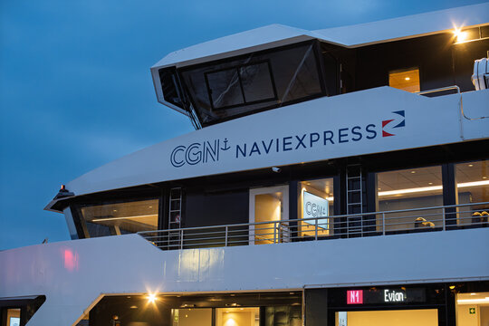 Lausanne, Switzerland, March 21. Close up of the sleek white hull and upper deck of the CGN Naviexpress passenger ferry with lit windows and an Evian destination sign during twilight