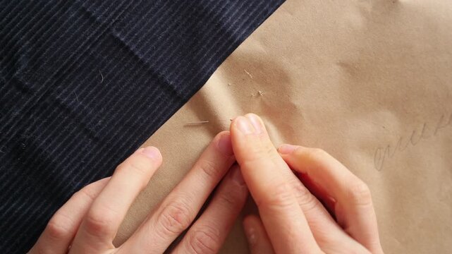 seamstress pins pattern to fabric with needles before sewing. concept of working from home, tailor develops a template. process of sewing on sewing machine. 4K high quality video