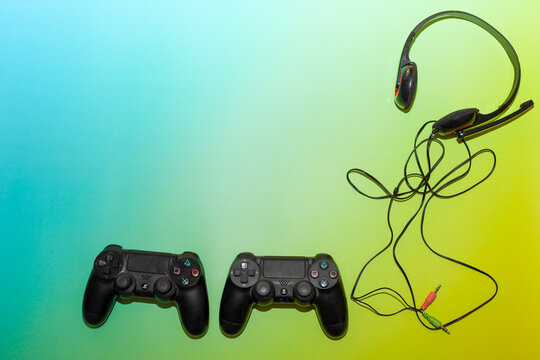 Lviv, Ukraine - March 19, 2026: A modern gaming set of two wireless controllers and a wired headset is harmoniously arranged on a bright blue-yellow gradient background.