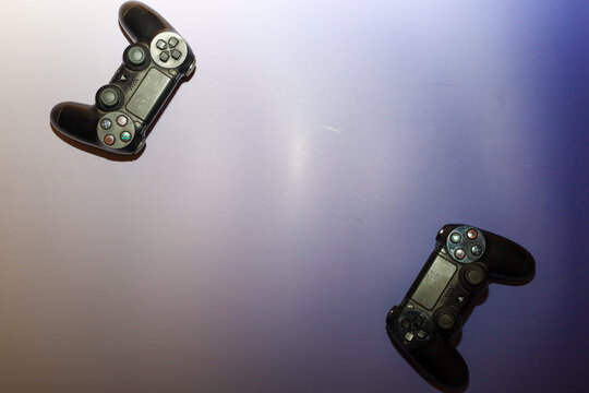 Lviv, Ukraine - March 19, 2026: ​A pair of black wireless PlayStation controllers sits on a gradient purple-to-white surface.