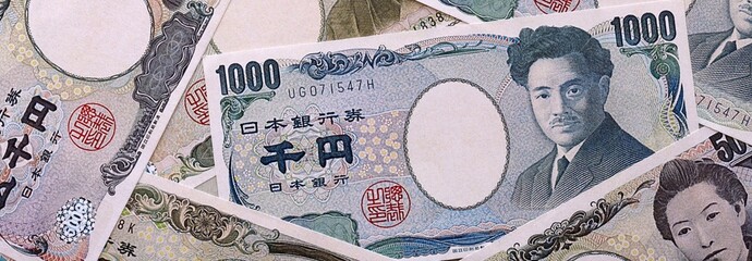 Japanese yen money bills pile on table. Japan banknotes of JPY currency close up. © Larysa