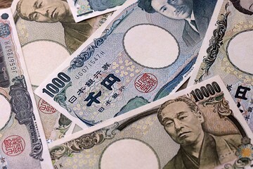 Japanese yen money bills pile on table. Japan banknotes of JPY currency close up. © Larysa