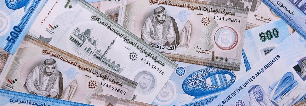 UAE dirham money bills pile on table. United Arab Emirates banknotes of AED currency close up.