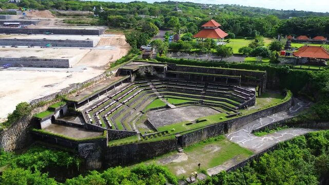 Aerial drone view of Gunung Payung Amphitheater in Bali, Indonesia. Scenic open-air amphitheater located on a cliffside near the coastline, surrounded by tropical landscape and ocean views.