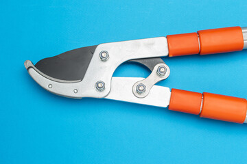 Fototapeta premium Close-Up of Orange Handled Pruning Shears on Bright Blue Background