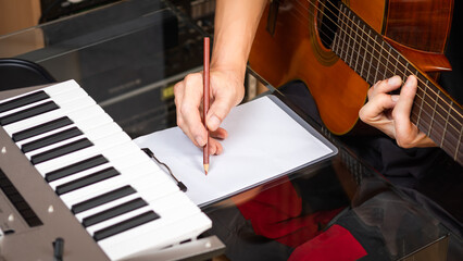 male musician writing a hit song by acoustic guitar in home studio. songwriting concept