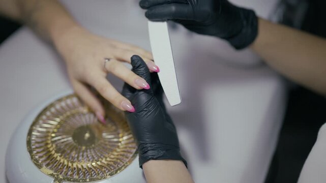 A nail technician meticulously files a client's nails, shaping them with precision and care. Providing a professional manicure service in a modern beauty salon environment.