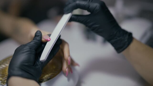 A professional nail technician meticulously files and shapes a client's nails during a manicure session. Enjoying a pampering nail care treatment at a modern beauty salon.