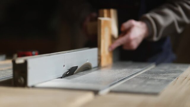 A woodworker operates a table saw, carefully guiding a piece of wood through the blade. The scene captures the precision and focus required in skilled carpentry.
