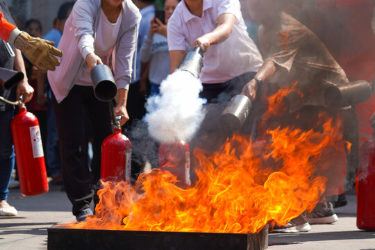 Employees firefighting training, Concept Employees hand using fire extinguisher fighting fire closeup