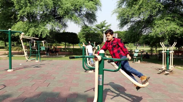 Elementary child exercising on single surfer pendel machine outdoor in nature.
