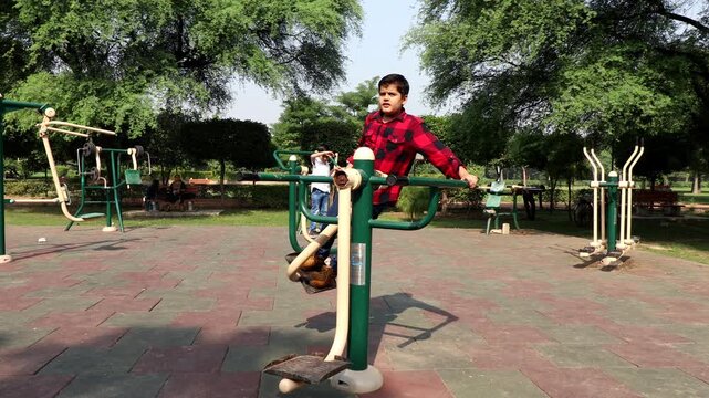 Elementary child exercising on single surfer pendel machine outdoor in nature.
