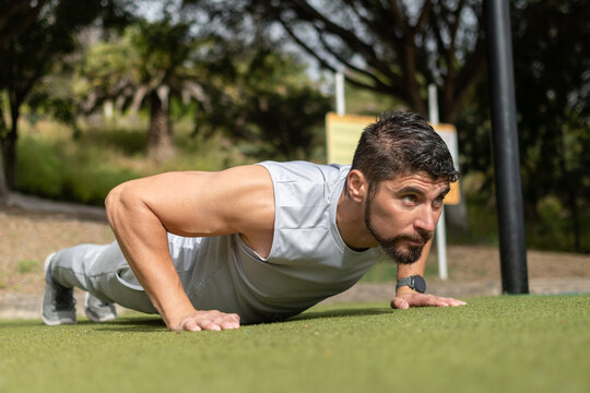 Young man doing push-ups workout in park outdoors