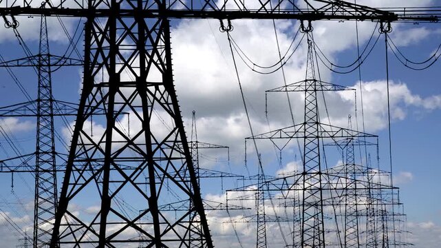 Wolken im Zeitraffer hinter den Stromleitungen und Strommasten einer 380 KV &Uuml;berlandleitung - FOTOMONTAGE