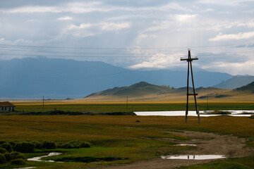 Fototapeta premium Rural landscape with power lines and rolling hills under dramatic sky
